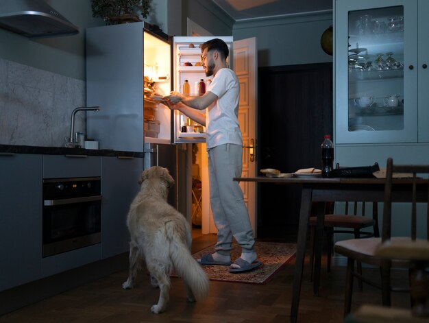 Homem com cachorro na cozinha tiro completo