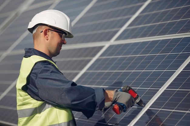 Homem com capacete branco perto de um painel solar