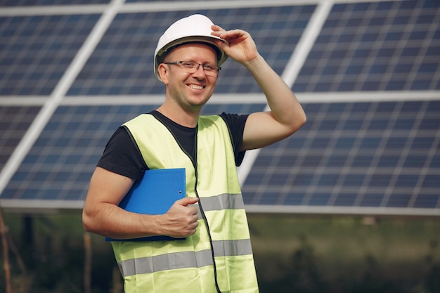 Homem com capacete branco perto de um painel solar