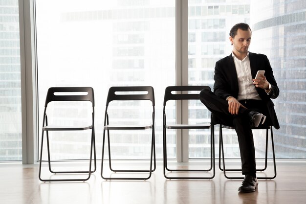 Homem com celular esperando sua vez na entrevista