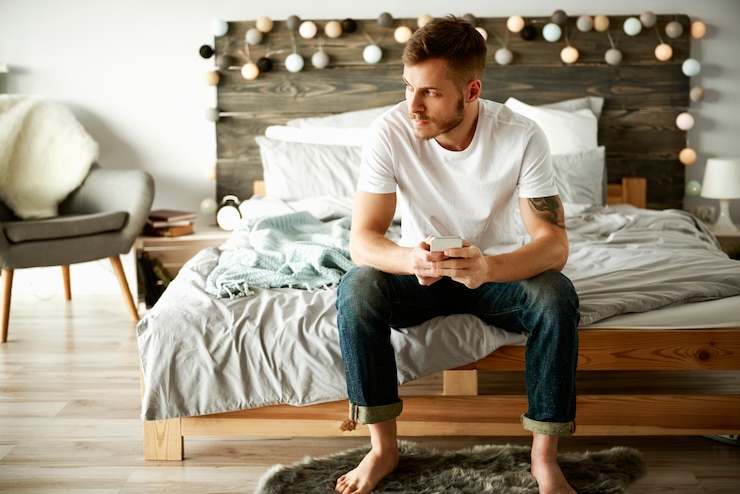 Foto grátis homem com celular sentado na cama