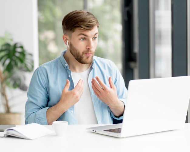 Homem com chamada de vídeo airpods no laptop