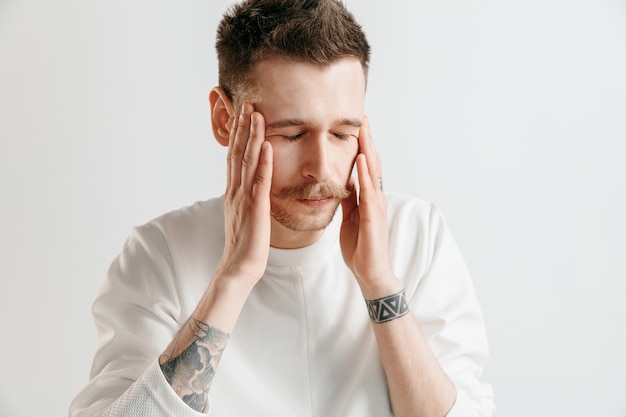 Homem com dor de cabeça. Homem de negócios em pé com dor isolada no fundo cinza do estúdio. Retrato de meio corpo masculino. Emoções humanas, conceito de expressão facial