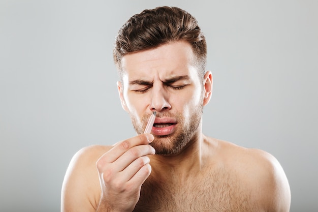 Homem com dor, remover os pêlos do nariz com uma pinça