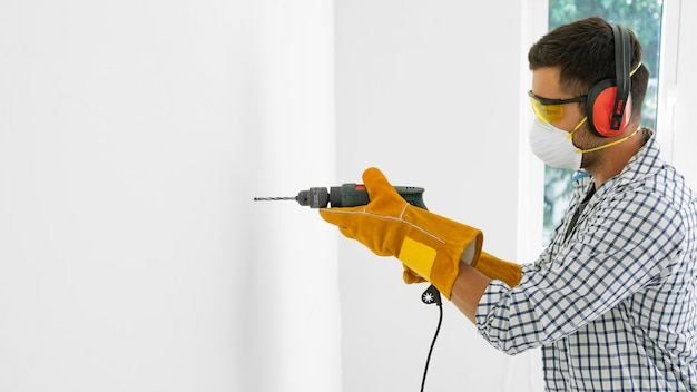 Foto grátis homem com equipamento de proteção de segurança com broca