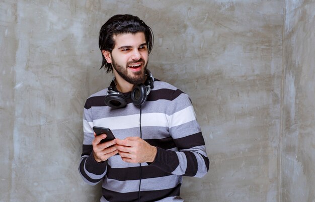 Homem com fones de ouvido checando mensagens ou playlists de música com energia positiva