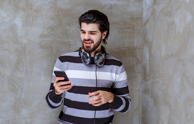 Homem com fones de ouvido checando mensagens ou playlists de música com energia positiva