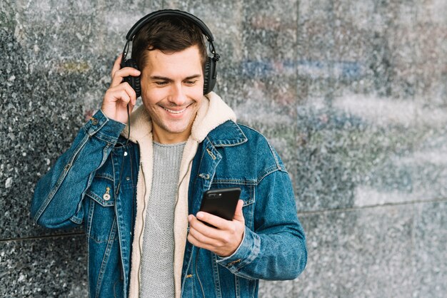 Homem com fones de ouvido e smartphone em ambiente urbano