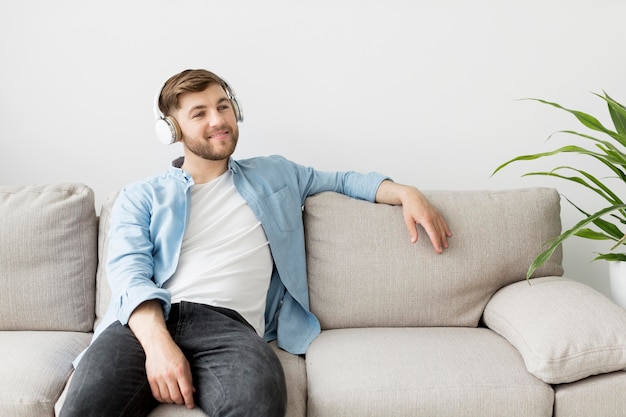 Homem com fones de ouvido no sofá