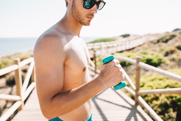 Foto grátis homem com haltere na praia