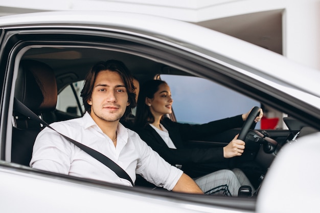 Homem com mulher em uma sala de exposições, escolhendo um carro