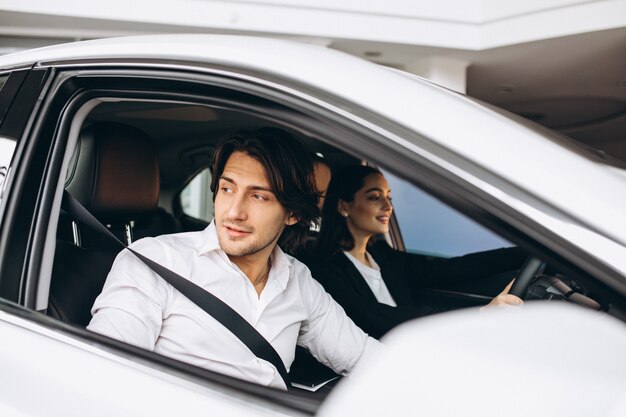 Homem com mulher em uma sala de exposições, escolhendo um carro