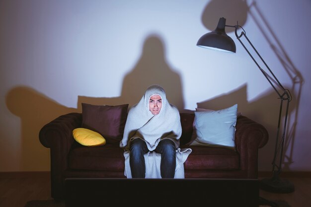 Homem com pano em volta da cabeça assistindo um filme