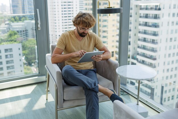 Homem com tablet sentado no sofá em um escritório moderno.