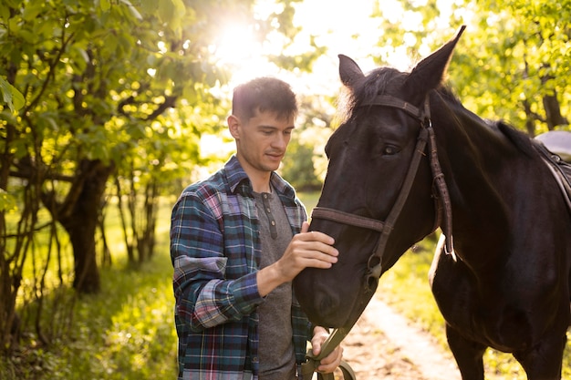 Homem com tiro médio acariciando o cavalo ao ar livre