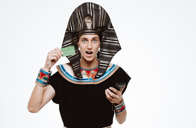 Homem com traje egípcio antigo segurando cartão de crédito e smartphone em branco