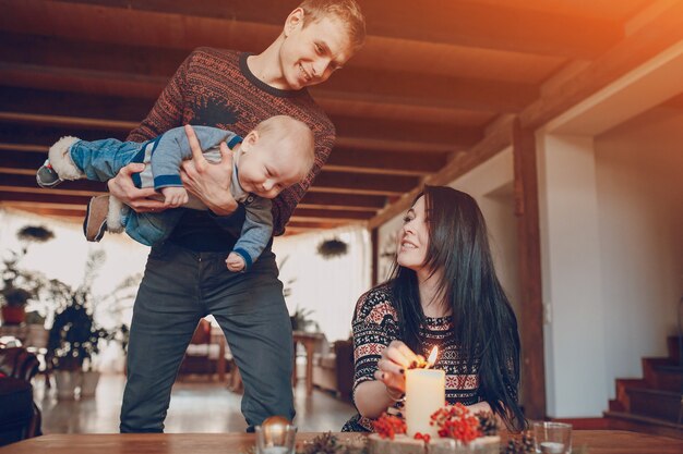 Foto grátis homem com um bebê em suas mãos olhando para sua esposa acender uma vela