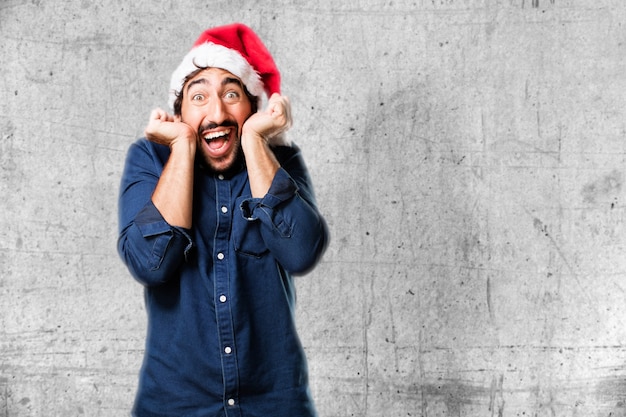 Homem com um chapéu de santa surpreendido com mãos na face