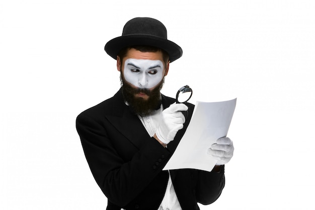 Homem com um rosto mime lendo através de lupa