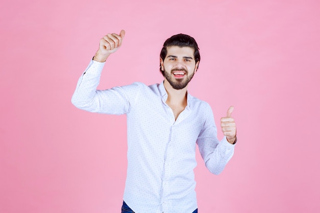 Homem com uma camisa branca aparecendo o polegar.