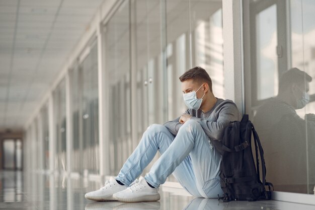 Homem com uma máscara sentado no corredor do hospital