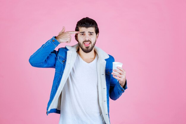 Homem com uma xícara de café apontando para a cabeça