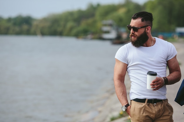 Homem com uma xícara de café olhando para a praia