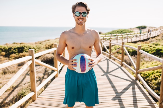 Homem com voleibol na praia