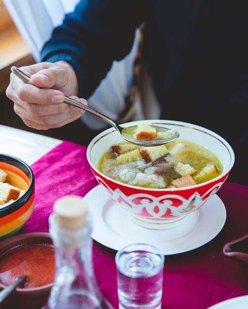 homem come sopa com biscoitos