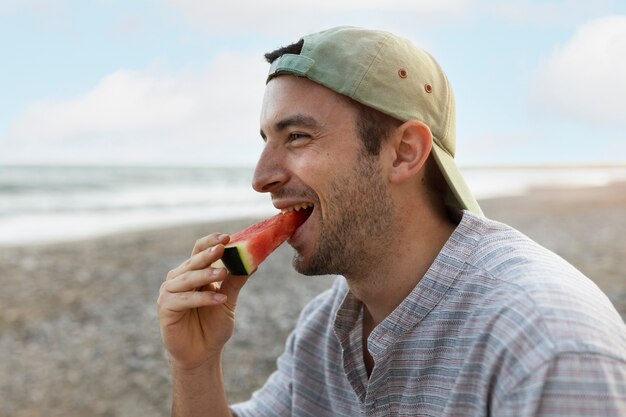 Homem comendo melancia na praia