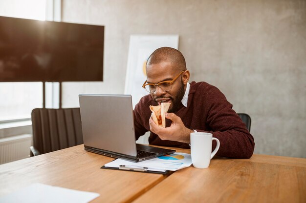 Homem comendo pizza durante o intervalo da reunião do escritório