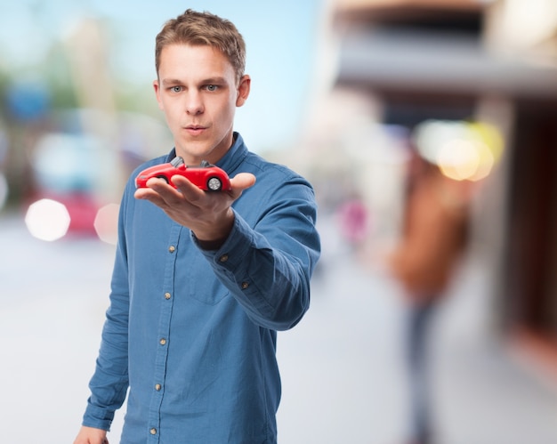 Homem concentrado olhando para um carro vermelho do brinquedo