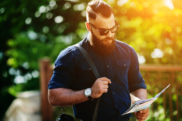 Homem concentrado que usa seu mapa ao pôr do sol