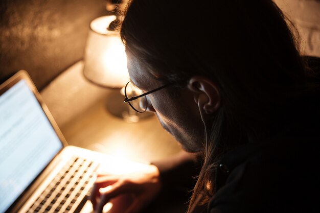 Homem concentrado usando o computador portátil em casa