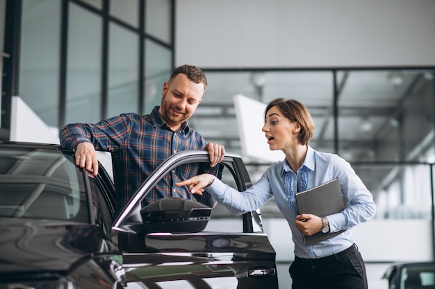 Homem considerável novo que escolhe um carro em uma sala de exposições do carro