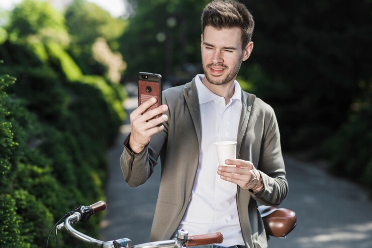 Foto grátis homem considerável novo que está com a bicicleta que toma o selfie no telefone celular