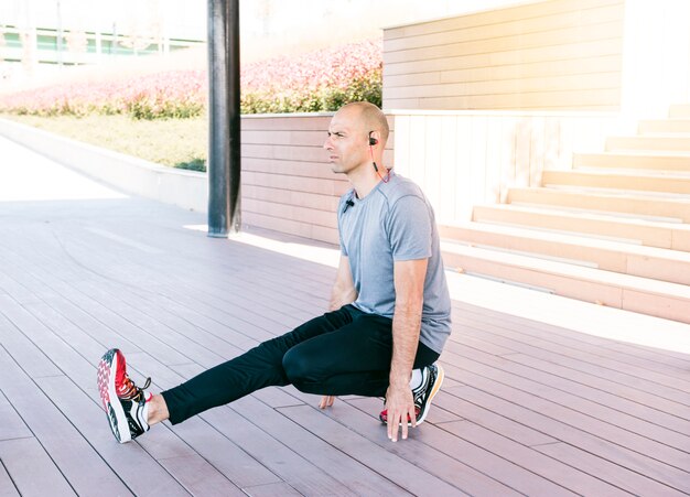 Homem considerável novo que estica o exercício no parque