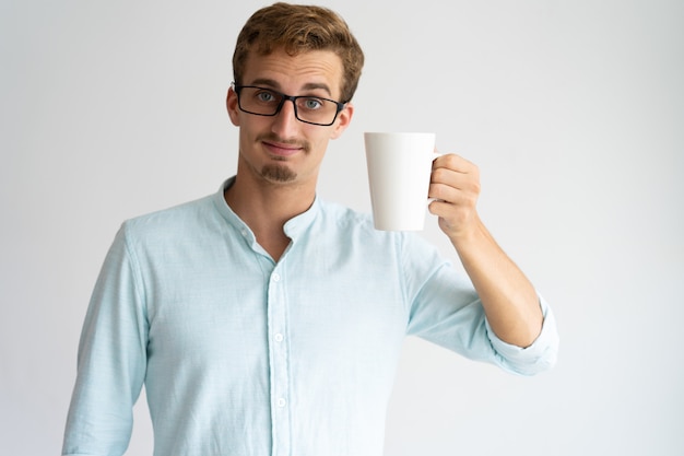 Homem considerável satisfeito que mostra a caneca e testa testa franzindo.