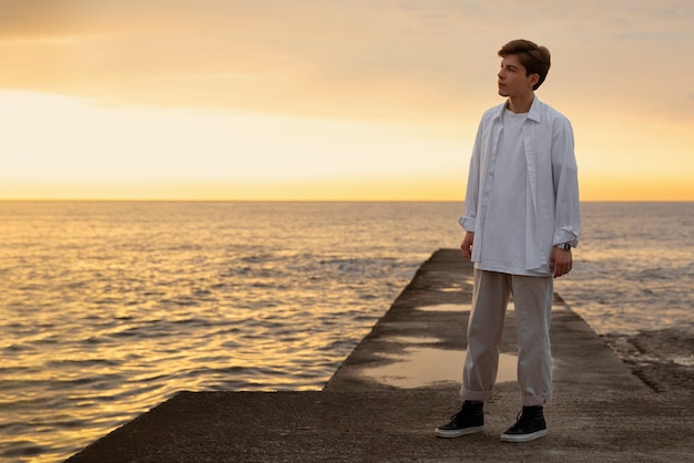 Foto grátis homem contemplativo de tiro completo à beira-mar