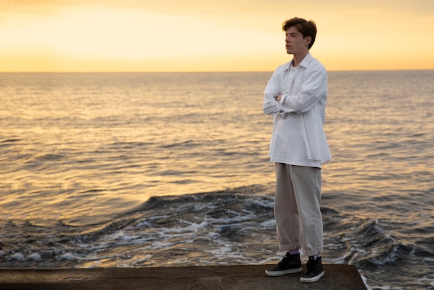 Foto grátis homem contemplativo de tiro completo à beira-mar