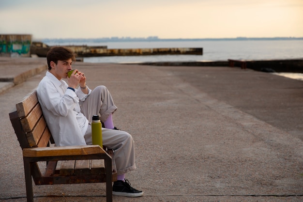 Homem contemplativo de tiro completo à beira-mar