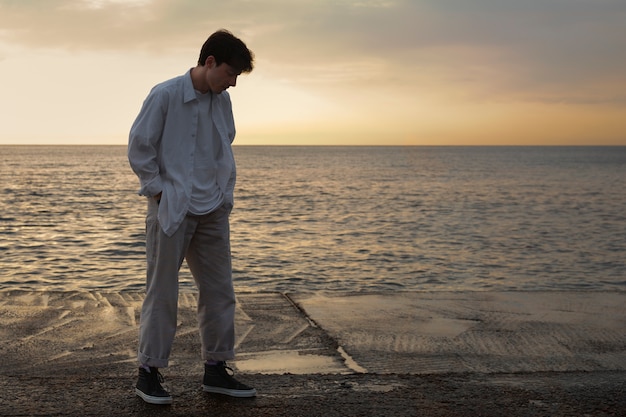 Foto grátis homem contemplativo de tiro completo à beira-mar