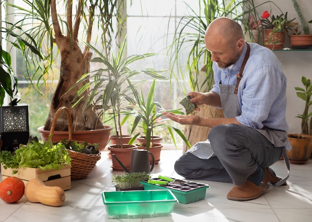 Foto grátis homem crescendo e cultivando plantas dentro de casa