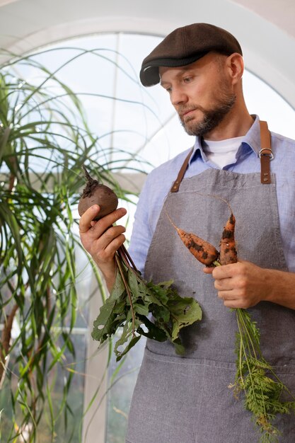 Homem cultivando legumes em seu jardim interno