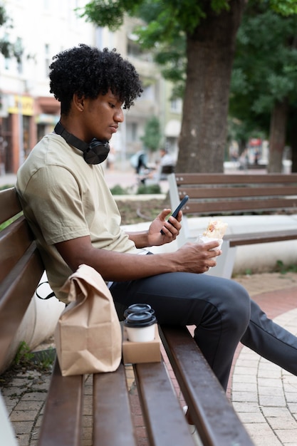 Homem curtindo comida para viagem ao ar livre