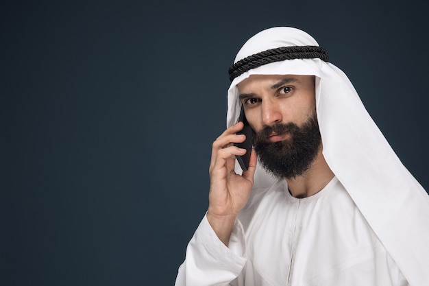 Foto grátis homem da arábia saudita em fundo azul escuro do estúdio