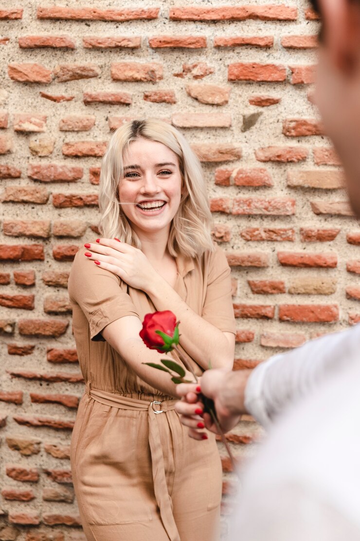 Foto grátis homem dando rosa para mulher feliz