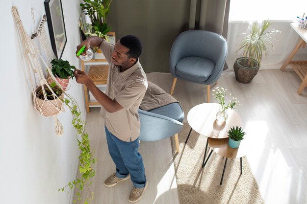 Homem de alto ângulo regar plantas em casa