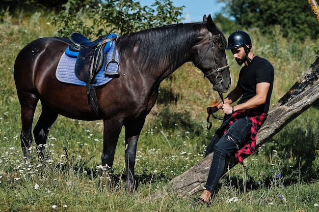 Homem de barba alta árabe usa capacete preto com cavalo árabe