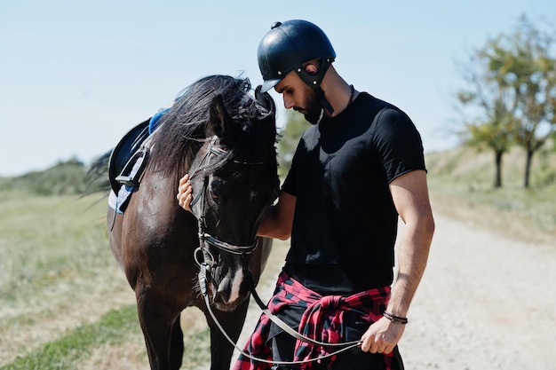 Homem de barba alta árabe usa capacete preto com cavalo árabe